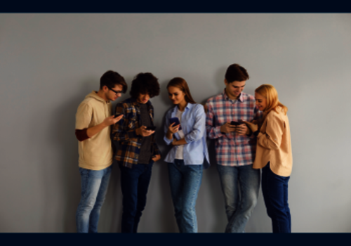 Junge Menschen, die nebeneinander stehen und Smartphones in den Händen halten.