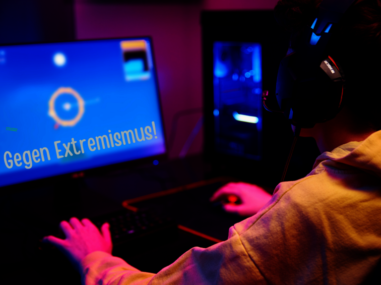 Junge Person spielt am Computer und es ist die Aussage "Gegen Extremismus!" am Monitor zu lesen 
