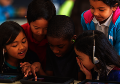 Kinder, die auf ein Tablet schauen, mit dem sie beschäftigt sind.