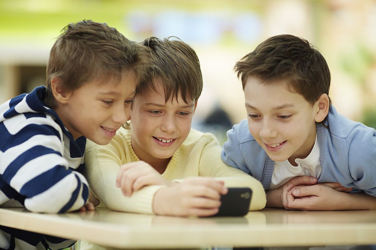ThinkstockPhotos-474780813_Copyright_shironosov.jpg Kinder, die auf ein Smartphone schauen