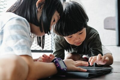 Zwei Kinder spielen an einem Tablet.