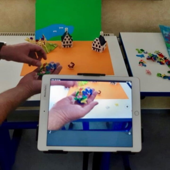 Ein Tablet, mit dem ein Foto von einer nachgebauten Szenerie mit Legosteinen gemacht wird.