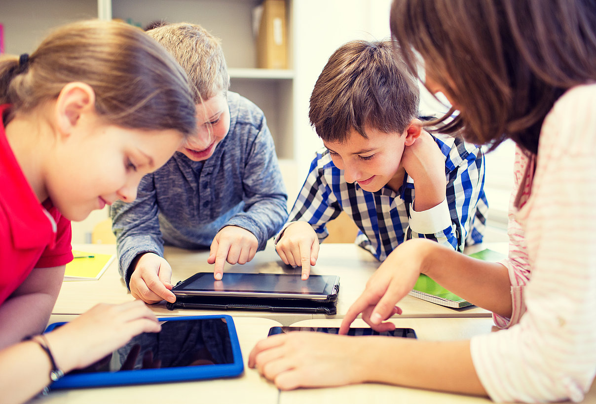 ThinkstockPhotos-490361666_dolgachov_mittlereGroeße.jpg Frau und drei Kinder tippen gemeinsam an mehreren Tablets