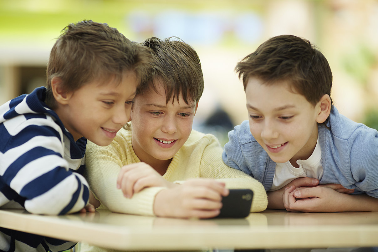 ThinkstockPhotos-474780813_Copyright_shironosov.jpg Kinder, die auf ein Smartphone schauen