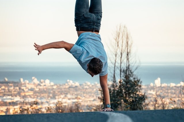 © Pexels/Stephan Louis Ein Mensch, der einen einarmigen Handstand auf einer Straße macht.