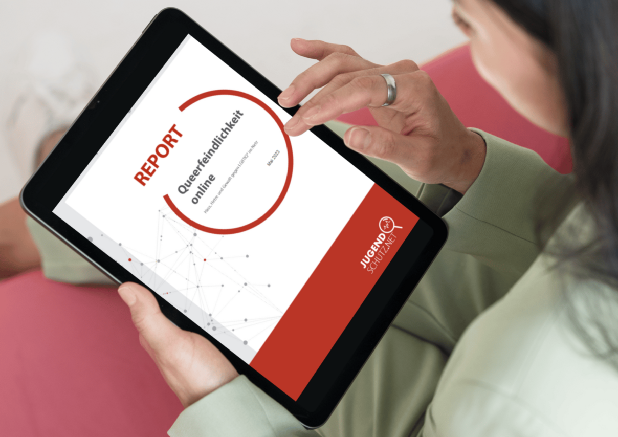 Eine Person, die sich auf einem Tablet den Report zu Queerfeindlichkeit online von jugendschutz.net anschaut.