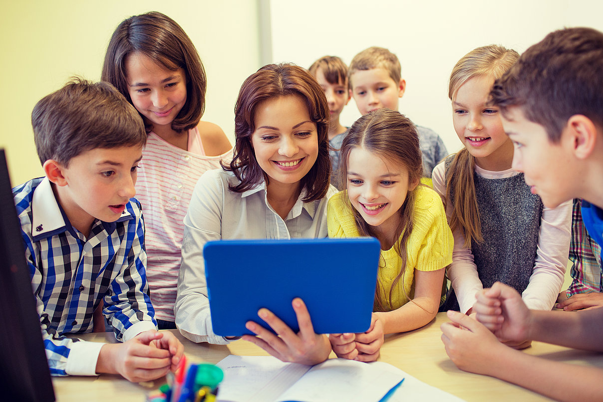 Lehrerin mit Kindern vor dem Tablet