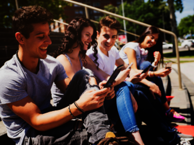 Sitzende junge Menschen, die ein Smartphone in den Händen halten.