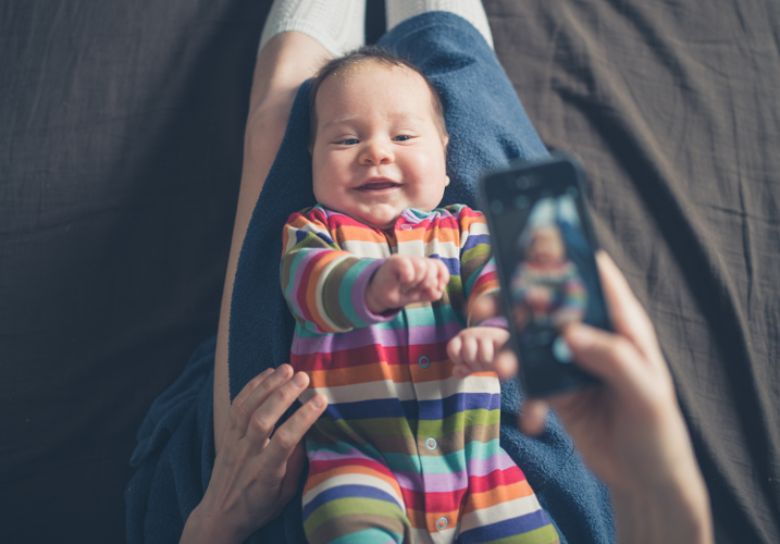 Baby wird mit Smartphone fotografiert 