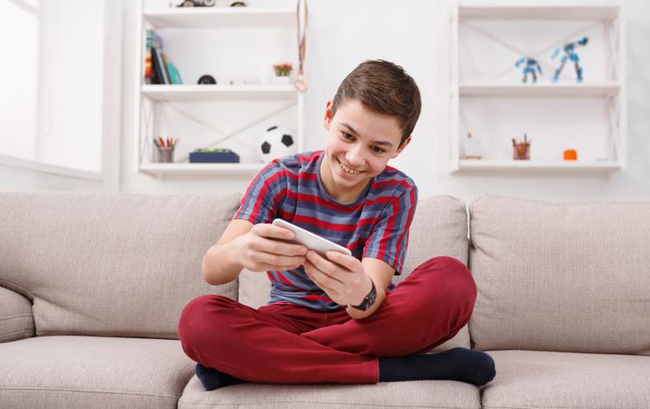 shutterstock_713270053.jpg Ein Junge beim Spielen auf dem Smartphone