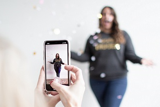 Youtube influencer.png Ein Mädchen wird von einem anderen Mädchen mit dem Smartphone aufgenommen.