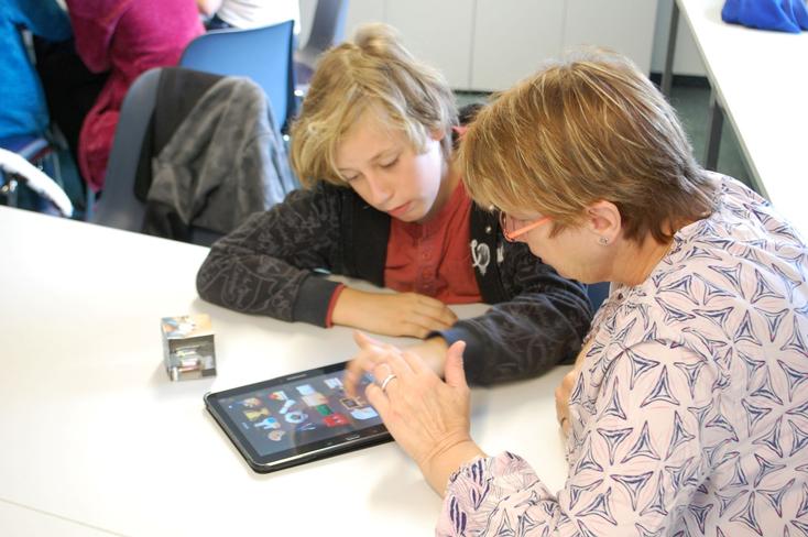 Eine Erwachsene und ein Kind sitzen zusammen an einem Tablet.