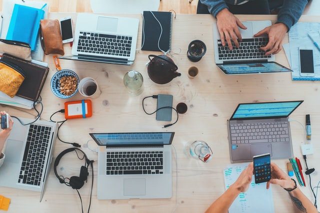unsplash_marvinmeier.jpg Laptops und andere digitale Geräte liegen auf einem Tisch und werden von Menschen benutzt.
