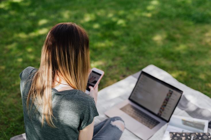 pexels-karolina-grabowska-4497814.jpg Eine Person, vor der ein Laptop steht und die ein Smartphone in den Händen hält.