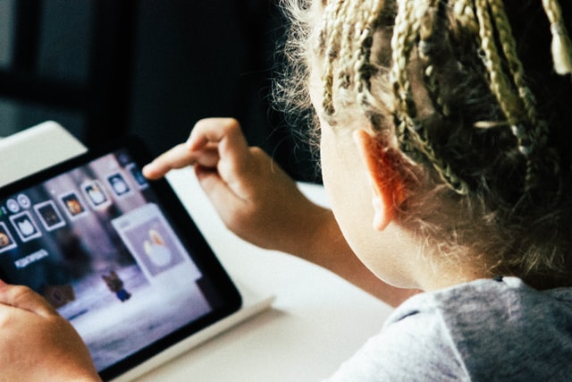 igor-starkov-unsplash.jpg Ein Kind, das auf einem Tablet etwas spielt.