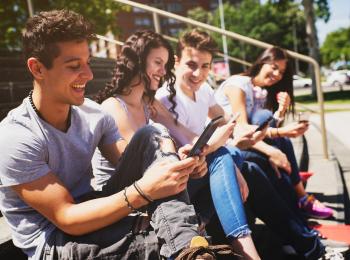 Sitzende junge Menschen, die ein Smartphone in den Händen halten. 