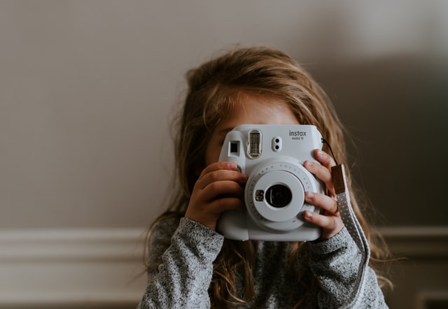 Ein Kind, das ein Fotoapparat vor sein Gesicht hält.